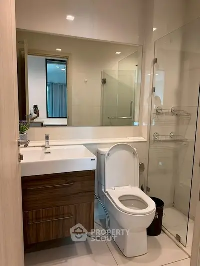 Modern bathroom with sleek fixtures and glass shower enclosure in a contemporary apartment.