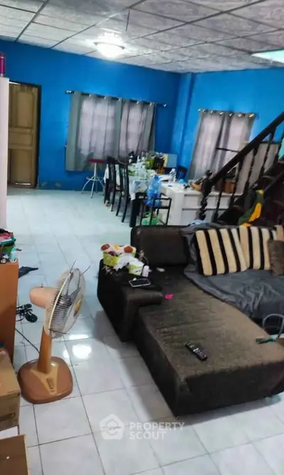 Spacious living room with blue walls, cozy sofa, and dining area, perfect for family gatherings.