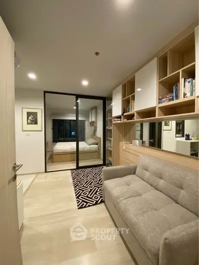Modern apartment with cozy living area and stylish bedroom separated by glass doors.