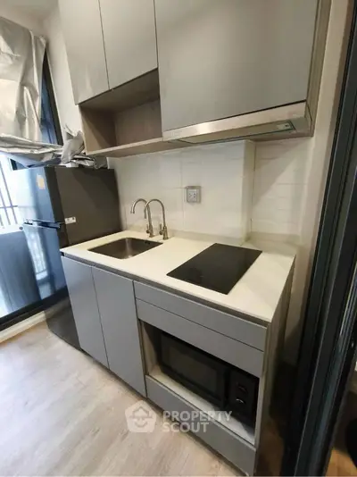 Modern compact kitchen with sleek cabinetry and built-in appliances in urban apartment.