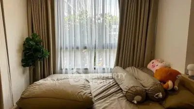 Cozy bedroom with plush toys and natural light through large window.