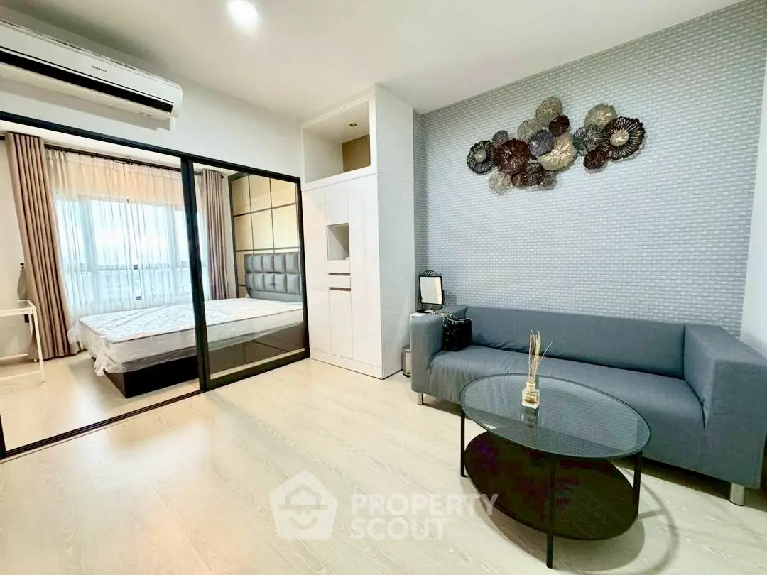 Modern apartment interior with stylish living room and cozy bedroom separated by glass doors.
