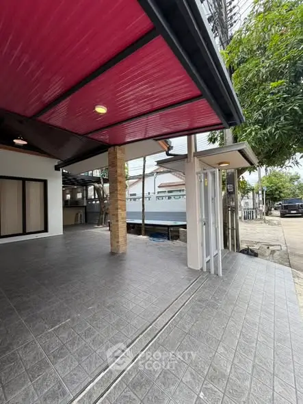 Modern covered outdoor area with tiled flooring and red ceiling, perfect for parking or gatherings.