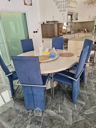 Modern kitchen with sleek blue chairs and marble flooring, featuring open layout and stylish decor.