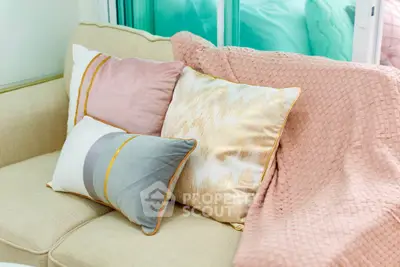 Cozy living room with stylish cushions and soft pink throw blanket on a beige sofa.