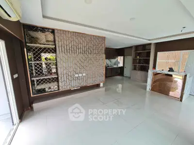 Spacious modern living room with stylish built-in shelving and open kitchen layout.