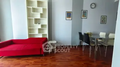 Modern living room with red sofa and dining area, featuring stylish wooden flooring and contemporary decor.