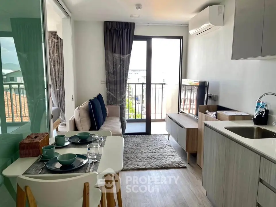 Modern living room with balcony view, stylish furniture, and open kitchen layout in a cozy apartment.