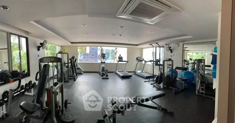 Spacious modern gym with state-of-the-art equipment and large windows for natural light.