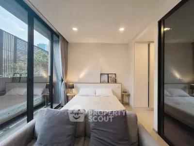 Modern bedroom with large windows and cozy decor, perfect for relaxation.