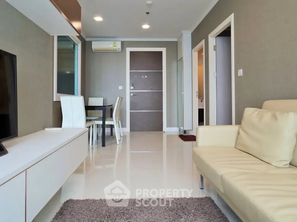 Modern living room with sleek furniture and neutral tones, featuring a cozy sofa and dining area.
