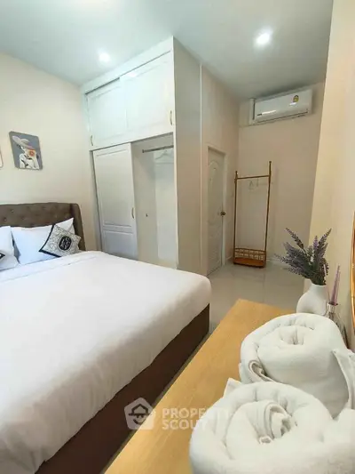 Cozy bedroom with modern decor and air conditioning, featuring a comfortable bed and ample storage space.