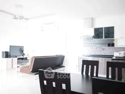 Bright modern living room with open kitchen and dining area, featuring sleek furniture and contemporary design.