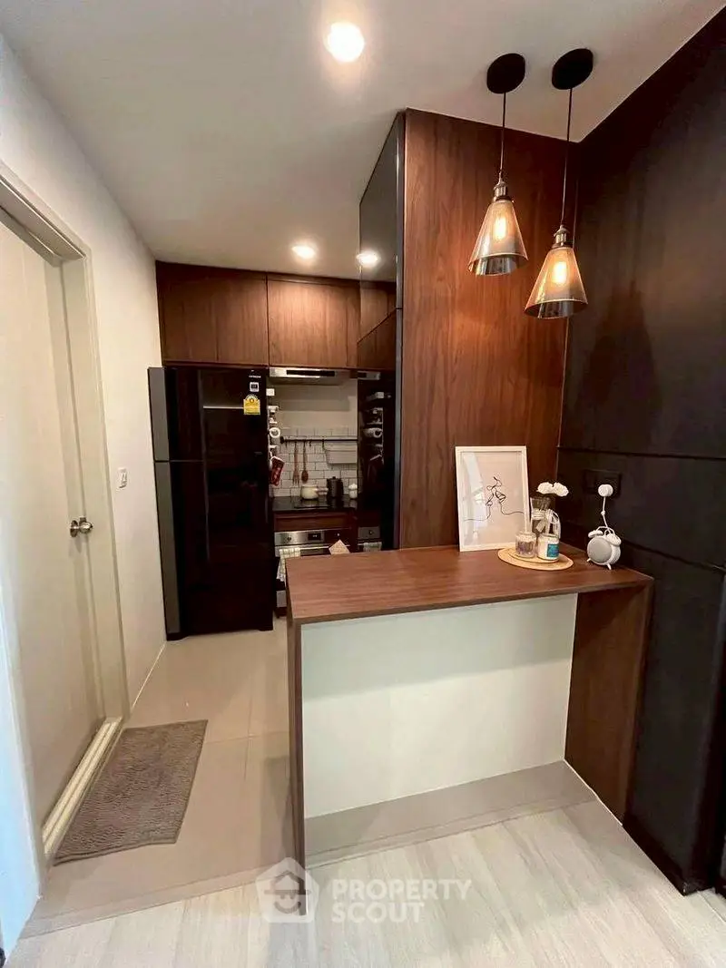 Modern kitchen with sleek design, featuring wooden cabinets and stylish pendant lights.