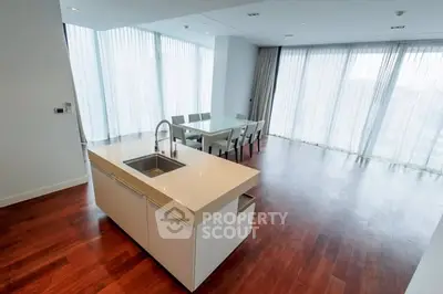 Spacious modern kitchen with open layout and dining area, featuring sleek design and ample natural light.
