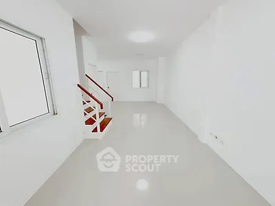 Spacious minimalist interior with white walls and staircase, ideal for modern living.