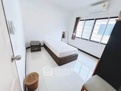 Bright minimalist bedroom with large window and modern furnishings.