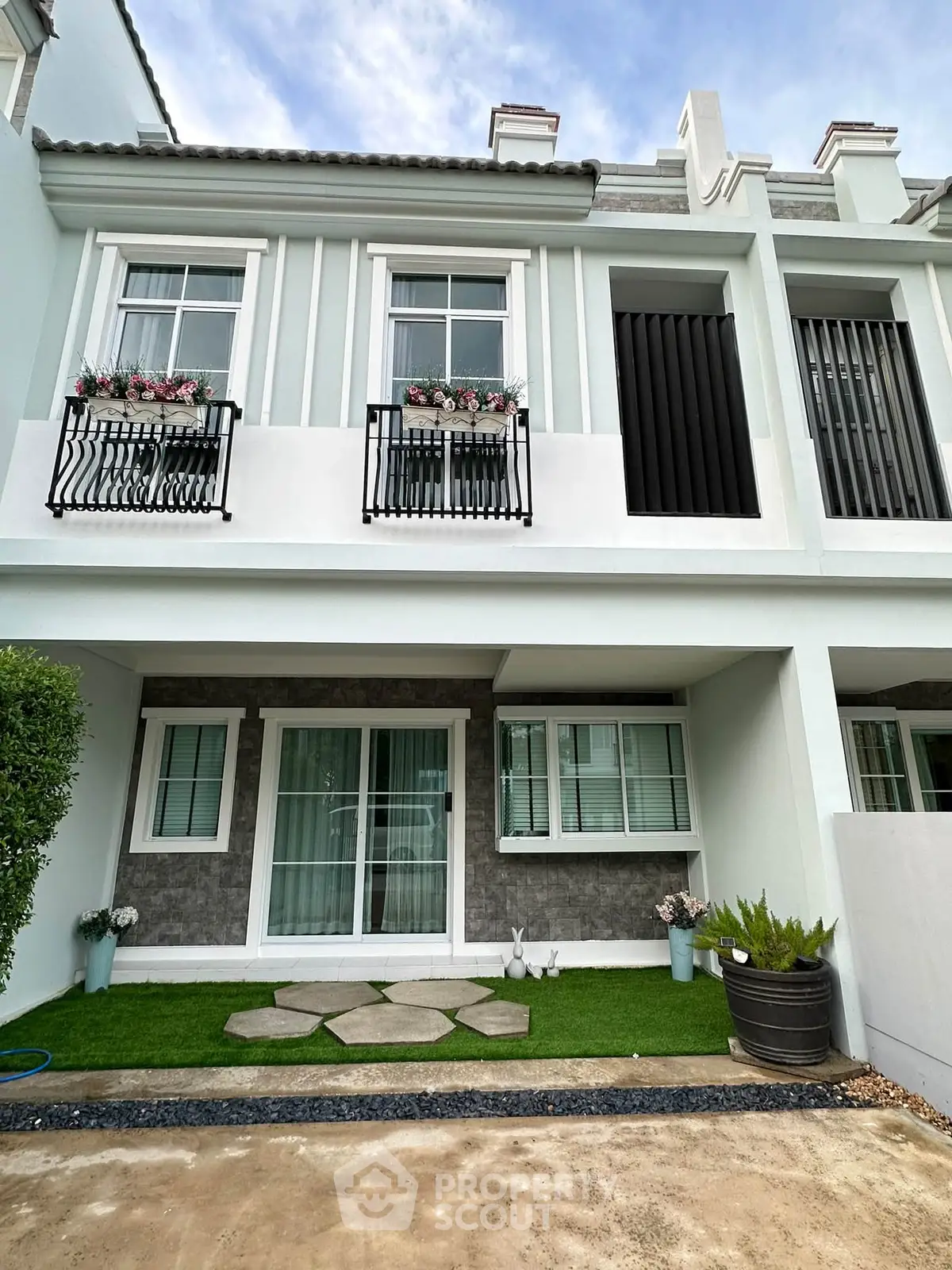 Charming townhouse exterior with elegant facade and lush greenery, perfect for modern living.