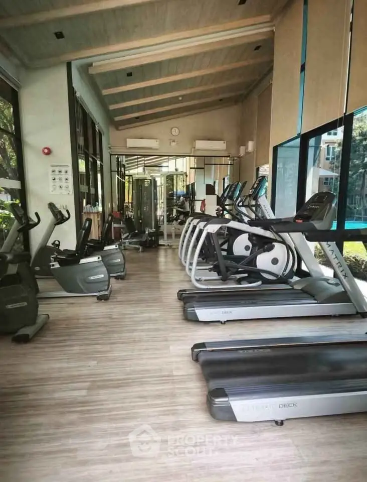 Modern gym with state-of-the-art equipment and large windows offering natural light.