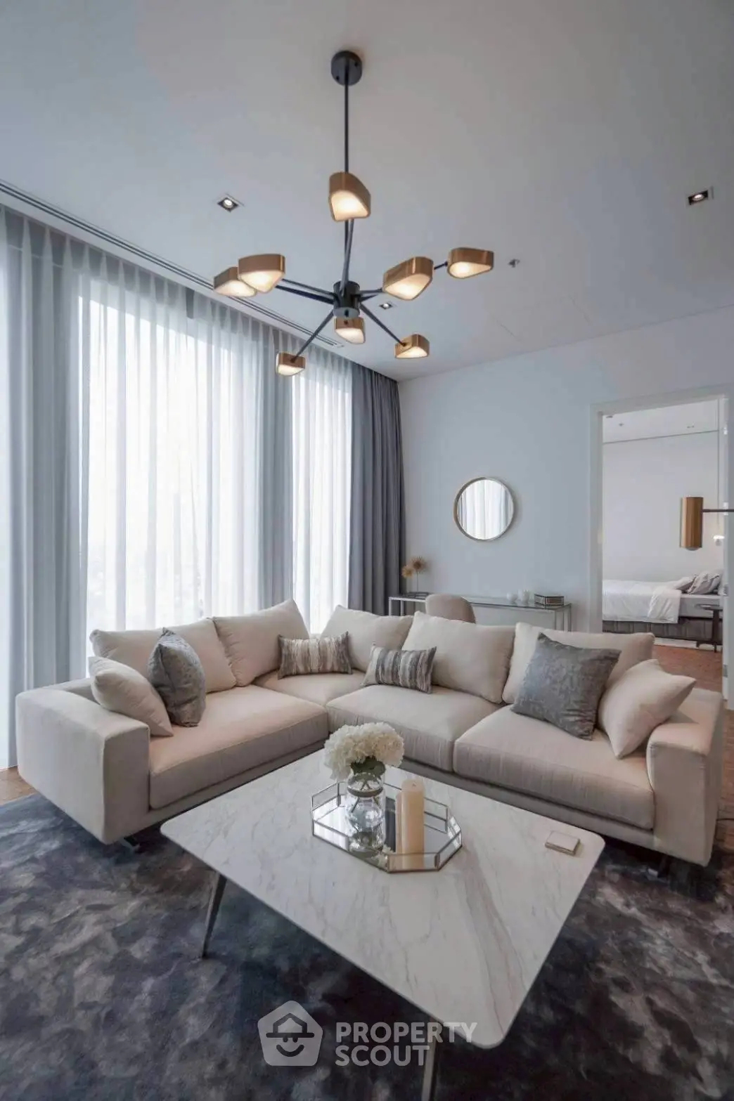 Elegant living room with plush sofa, modern chandelier, and marble coffee table in a stylish apartment.