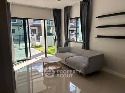 Bright living room with modern sofa and large windows overlooking garden.