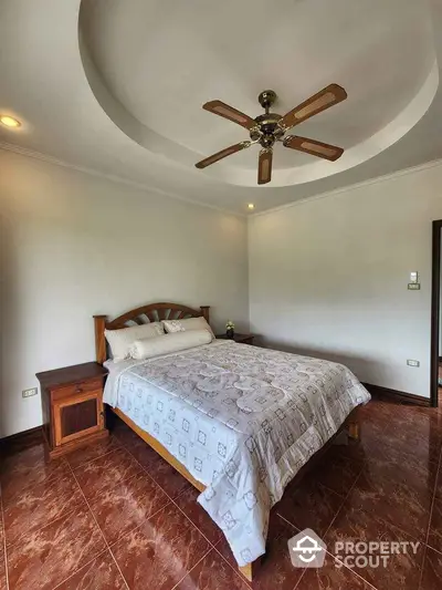 Spacious bedroom with elegant ceiling fan and cozy wooden furniture