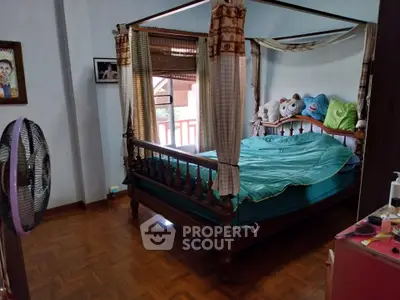 Charming bedroom with wooden flooring and canopy bed, featuring plush toys and natural light.