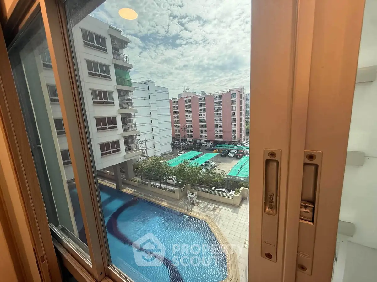 Stunning view from apartment window overlooking pool and residential buildings.