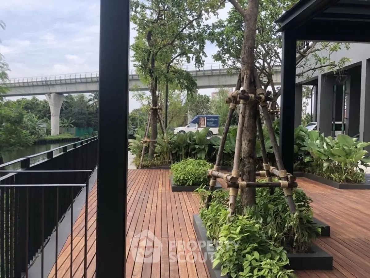 Modern garden terrace with lush greenery and wooden decking near urban rail line.