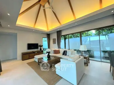 Luxurious living room with high ceiling and modern decor, featuring large windows and elegant lighting.