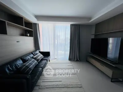 Modern living room with sleek furniture and large TV, featuring floor-to-ceiling windows and stylish decor.