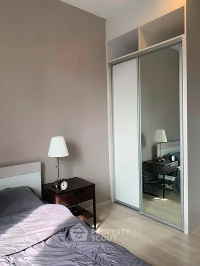Cozy bedroom with mirrored wardrobe and stylish bedside lamp