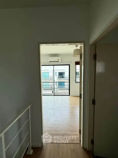 Bright and airy apartment with balcony view, featuring modern wooden flooring and ample natural light.