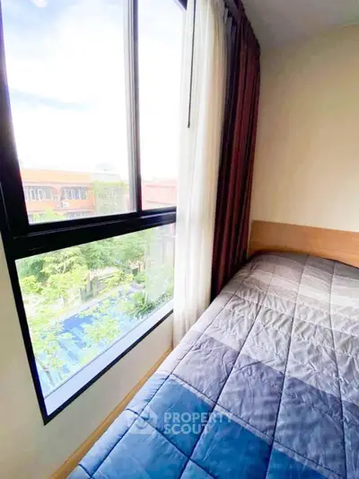 Cozy bedroom with large window offering a serene view, perfect for relaxation and natural light.