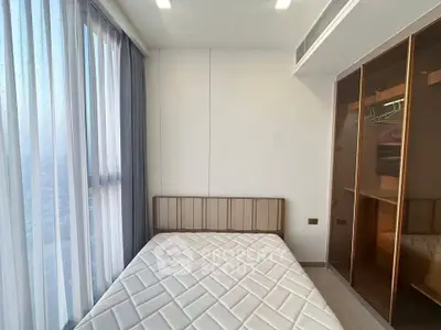 Modern bedroom with large window and built-in closet in high-rise apartment.