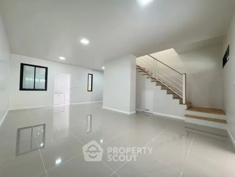 Spacious modern living room with glossy tile flooring and staircase