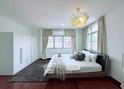 Spacious bedroom with modern decor and large windows for natural light.