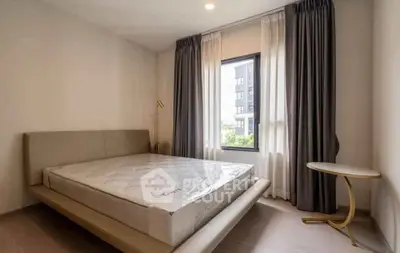 Modern bedroom with large window and stylish curtains, featuring a sleek bed and elegant side table.