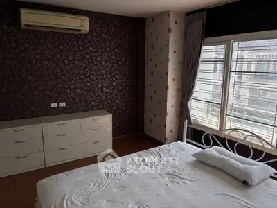 Spacious bedroom with modern decor and large window offering natural light.