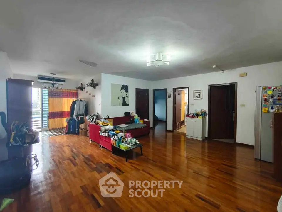 Spacious living room with wooden flooring and modern decor in a stylish apartment.