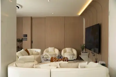 Luxurious modern living room with elegant furniture and large TV, perfect for relaxation and entertainment.