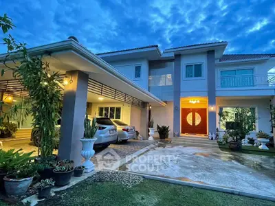 Stunning two-story home with elegant entrance and spacious driveway at dusk.