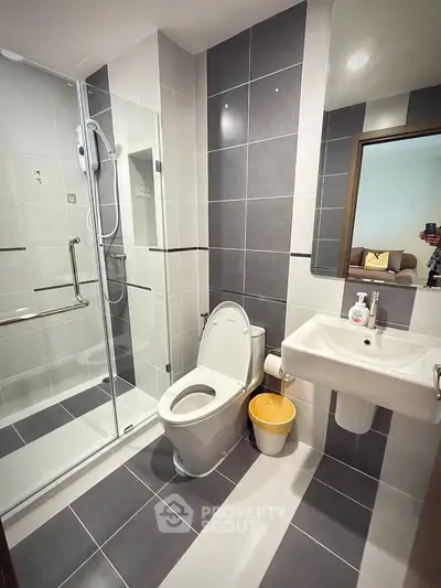 Modern bathroom with sleek design, featuring a glass shower enclosure and contemporary fixtures.