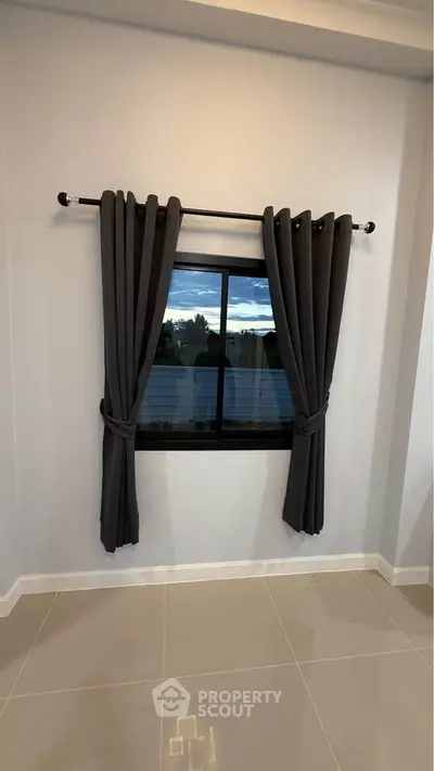 Minimalist room with sleek dark curtains and a scenic window view, perfect for modern living.