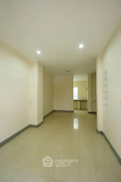 Spacious hallway with tiled flooring leading to a kitchen area, perfect for modern living.
