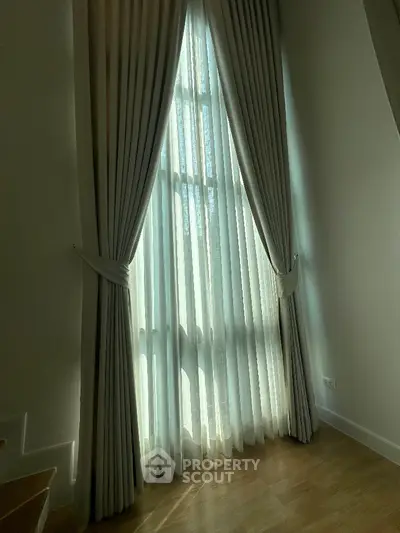 Elegant floor-to-ceiling window with luxurious drapes in a modern home interior.
