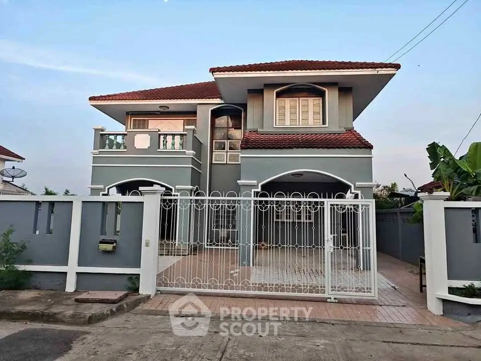 Charming two-story house with red roof and spacious gated driveway