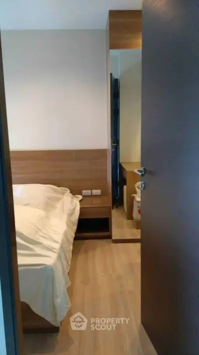 Cozy bedroom with wooden flooring and modern furnishings in a stylish apartment.
