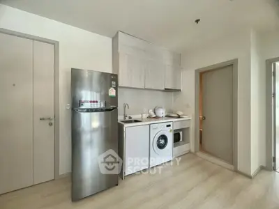 Modern kitchen with stainless steel fridge, washing machine, and sleek cabinetry in a compact layout.