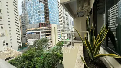 Urban balcony view with lush greenery and modern high-rise buildings.